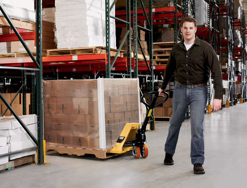 Man pulling CAT pallet jack through warehouse aisle