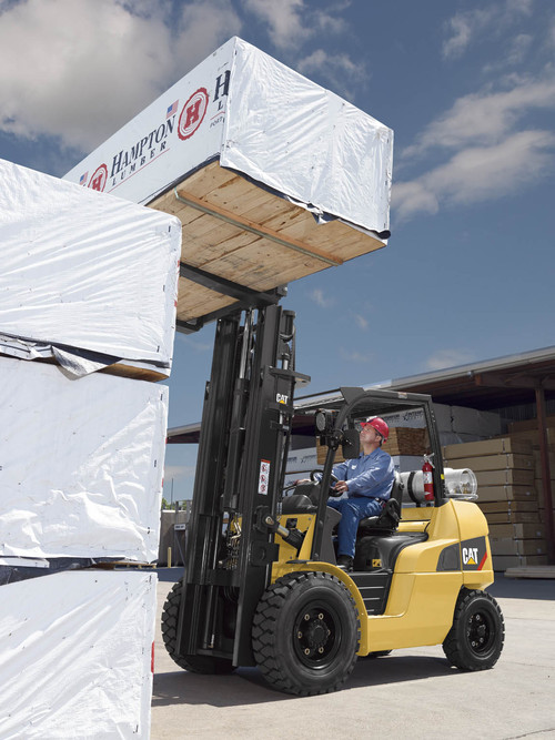 Front close up view of man transporting wood bundle with 8,000 – 12,000 lb. pneumatic tire CAT forklift