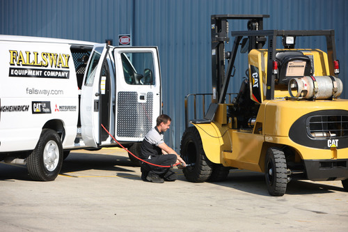 Fallsway employee pumping air into CAT forklift tires